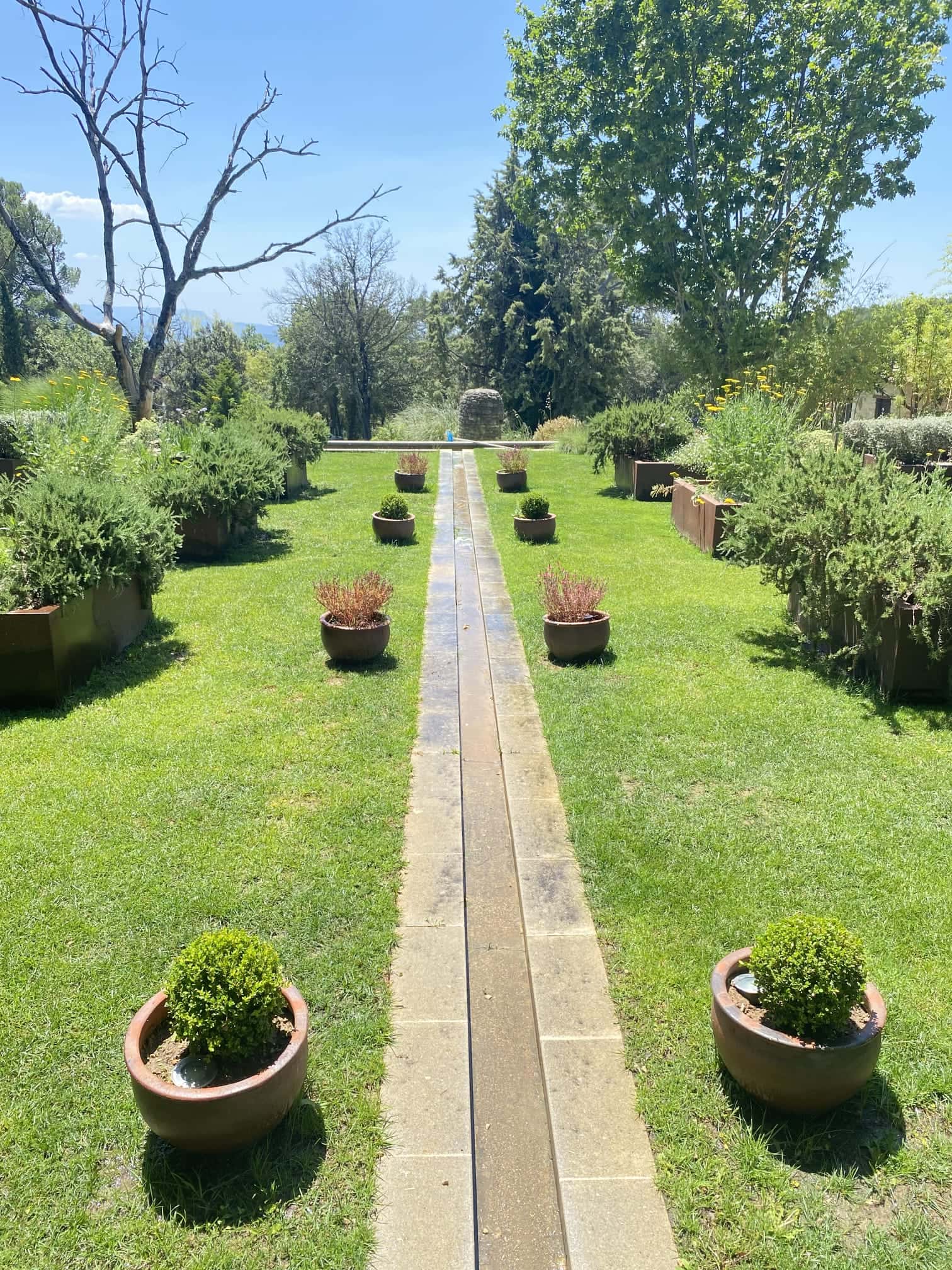 Conception d'un jardin contemporain avec allée symétrique, pots en terre cuite et fontaine centrale par Jardin Aixeption à Aix-en-Provence